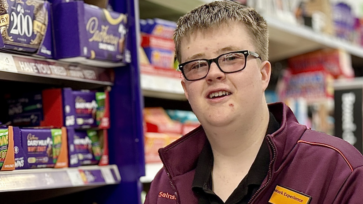 A young adult working at Sainsburys as part of the Post 16 Specialist Provision